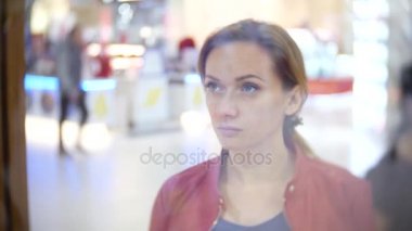 Depodaki cam vitrin, arayan bir kadın. 4k, arka plan bulanıklık.