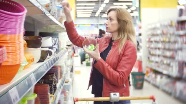 超市用具的选购。一个女人在超级市场里选择厨房用具。4k、背景模糊 — 图库视频影像