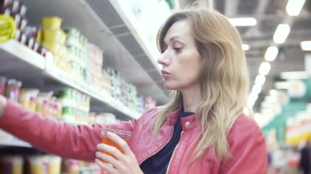 Mujer joven eligiendo comida en la tienda de comestibles, mujer comprando en el supermercado. 4k, desenfoque de fondo — Vídeos de Stock
