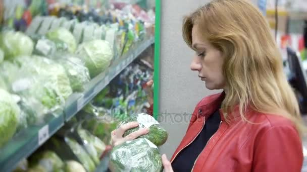 Jovem mulher escolhendo comida no supermercado, mulher comprando no supermercado. 4k, borrão de fundo — Vídeo de Stock