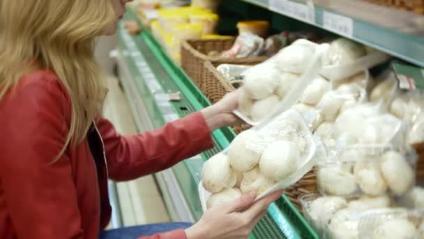 Jovem mulher escolhendo comida no supermercado, mulher comprando no supermercado. 4k, borrão de fundo — Vídeo de Stock