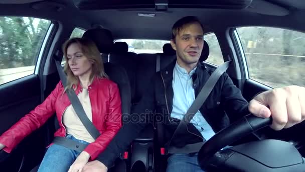 Man and woman ride in a car in an unfamiliar area, fastened with seat belts, 4k — Stock Video
