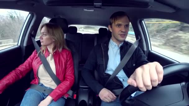 Man and woman ride in a car in an unfamiliar area, fastened with seat belts, 4k — Stock Video