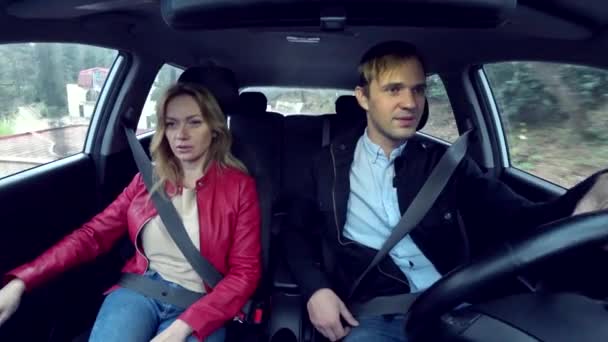 Man and woman ride in a car in an unfamiliar area, fastened with seat belts, 4k — Stock Video