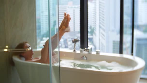 아름 다운 여자 창 럭셔리 욕실에서 목욕을 편안 하 게 즐기는. 라이프 스타일과 뷰티 케어 개념입니다. 보기 창에서 마천루를 합니다. 4 k — 비디오