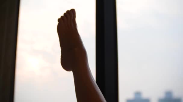 4k, kvinnliga ben i badrummet av hotellrum. kvinna rakar benen i badrummet på bakgrunden i ett fönster med utsikt över skyskraporna. närbild — Stockvideo