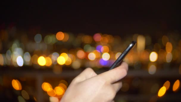 Manos Usando Smartphone al anochecer en la ciudad, Close Up. lectura en el teléfono celular, el uso de las redes sociales de aplicaciones, mensajes de texto. Fondo borroso de luces de la calle nocturna. 4k — Vídeo de stock