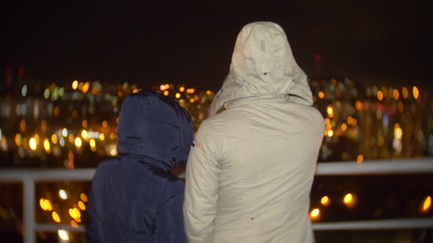 El hombre y la mujer están de pie con la espalda. mirando hacia el futuro, paisaje urbano sobre un borroso fondo nocturno de luz abstracta bokeh. 4k — Vídeos de Stock