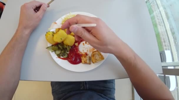 Ein Mann isst gebratenes Fleisch mit Bratkartoffeln in Gewürzen. 4k. Ego-Shooting, Ansicht von oben. — Stockvideo