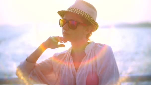 Mujer joven con sombrero y gafas de sol viajando en barco al atardecer. 4k — Vídeo de stock