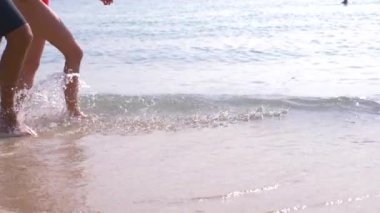 Birkaç açık güneşli bir günde Sahilde yürüyüş severler. bacaklar deniz kıyısı yürüyen bir kadın ve bir adam. 4k, ağır çekim