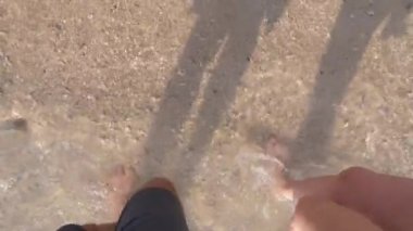 Birkaç açık güneşli bir günde Sahilde yürüyüş severler. bacaklar deniz kıyısı yürüyen bir kadın ve bir adam. 4k, ağır çekim
