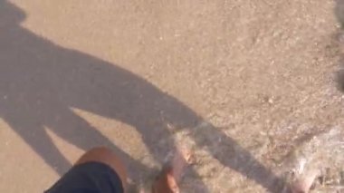 Birkaç açık güneşli bir günde Sahilde yürüyüş severler. bacaklar deniz kıyısı yürüyen bir kadın ve bir adam. 4k, ağır çekim