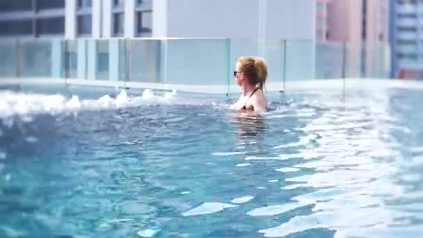 Ung vacker kvinna i poolen på takterrassen med utsikt över staden. Glad tjej njuter av semester. Framgång, begreppet lycka. 4k — Stockvideo