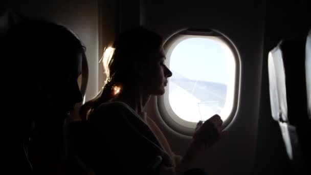 Femme dans un avion avec des enfants sur un fond hublot. 4k — Video