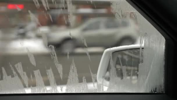 La voiture longe la route d'hiver, une vue de l'intérieur à travers un verre glacé mal nettoyé. 4k — Video