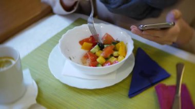 bir kadın bir smartphone kullanarak bir kafede yemek yiyorlar. 4k