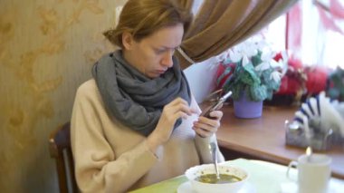 bir kadın bir smartphone kullanarak bir kafede yemek yiyorlar. 4k