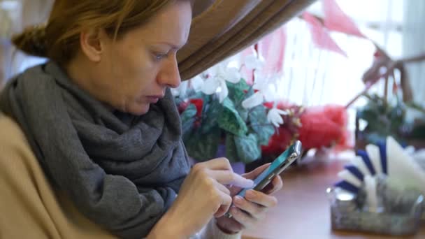 Una mujer está cenando en un café con un teléfono inteligente. 4k — Vídeo de stock