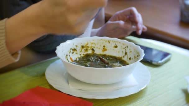 Una mujer está cenando en un café con un teléfono inteligente. 4k — Vídeo de stock