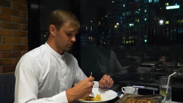 Pareja feliz hablando y cenando en un bar con vistas a los rascacielos, por la noche, 4k, fondo borroso — Vídeo de stock