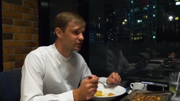 Pareja feliz hablando y cenando en un bar con vistas a los rascacielos, por la noche, 4k, fondo borroso — Vídeo de stock