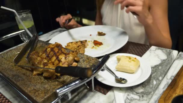 Alguien para hablar y cenar en el bar con vistas a los rascacielos, por la noche, 4k, difuminar el fondo. Las manos femeninas cortan un trozo de filete con un cuchillo y un tenedor . — Vídeos de Stock