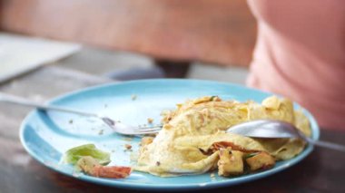 Omlet deniz ürünleri ile tavada kızartılmış nişasta erişte. 4 k yakın çekim. bir kadın bir kaşık ve çatal Tayland ulusal yemek yiyor.