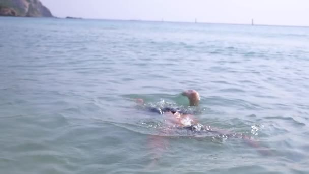 4 k、スローモーション撮影、若い男はサングラスで海にダイブします。現れる — ストック動画