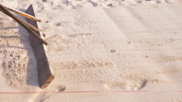 Кто-то выравнивает песок на пляже. 4к, замедленная съемка, крупный план, ноги человека, который делает уборку пляжа . — стоковое видео