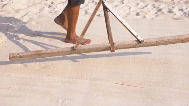 Alguien está nivelando la arena en la playa. 4k, cámara lenta, primer plano, las piernas de un hombre que hace la limpieza de la playa . — Vídeos de Stock