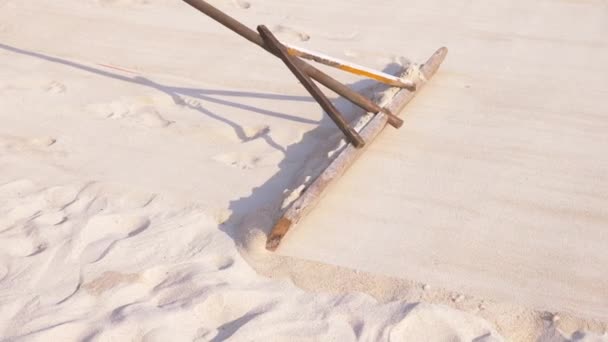 Alguien está nivelando la arena en la playa. 4k, cámara lenta, primer plano, las piernas de un hombre que hace la limpieza de la playa . — Vídeo de stock