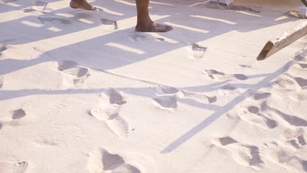 Qualcuno sta livellando la sabbia sulla spiaggia. 4k, rallentatore, primo piano, le gambe di un uomo che fa la pulizia della spiaggia . — Video Stock