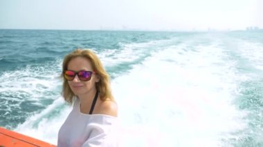 Güzel bir kadın geminin kıç üzerinde duruyor. Dalgalar içinde geçmiş, ağır çekim, 4k