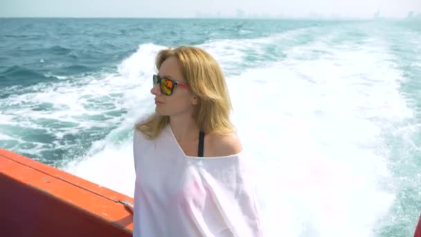 O femeie frumoasă stă pe pupa navei. Valuri în fundal, mișcare lentă, 4k — Videoclip de stoc