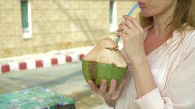 Kadın içecekler Hindistan cevizi suyu bardağı taşıran damla, 4 k, yakın çekim, ağır çekim