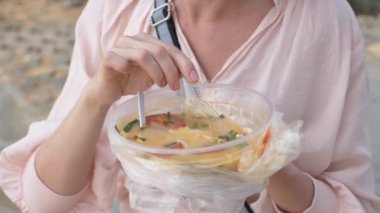 kadın Tom Yam sahilde, 4 k yavaş hareket oturan yeme Tay çorba