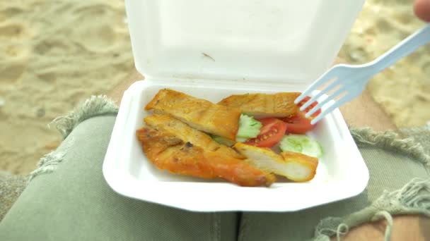 Chutné smažené kuře barbecue, styl thajské kuchyně v kontejneru, thajskou pouliční jídlo, někdo jí kuře na pláži. 4k, pomalý pohyb — Stock video