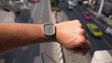 yakın çekim. kol saati üzerinde bir el, bir şehir ile yüksek trafik sokak çerçevede bir mans. Yavaş hareket, arka plan bulanıklık. 4k