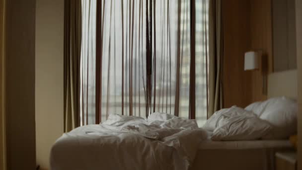 Hombre en pantalones cortos abre las cortinas de la ventana, vista desde la ventana a los rascacielos. 4k — Vídeo de stock