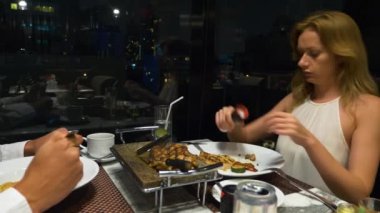 Konuşmaya ve bir barda yemek yerken mutlu çift gökdelenler, akşamları bakan, 4k, arka plan bulanıklık