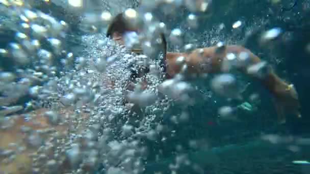 Un jeune homme blanc beau faisant un selfie sous-marin sur une caméra d'action. Portrait d'un jeune homme avec des lunettes se déplaçant devant la caméra sous l'eau. 4k — Video