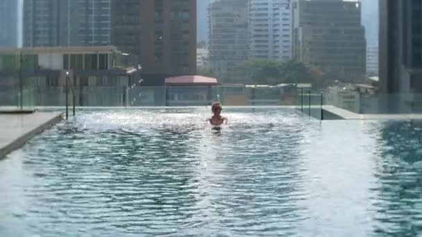 Mladá krásná žena v střešní bazén s výhledem na město. Šťastná dívka těší dovolená. Úspěch, pojmu štěstí. 4k — Stock video