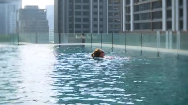 Молода красива жінка в басейні даху з видом на місто. Щаслива дівчина насолоджується відпусткою. Успіх, концепція щастя. 4k — стокове відео