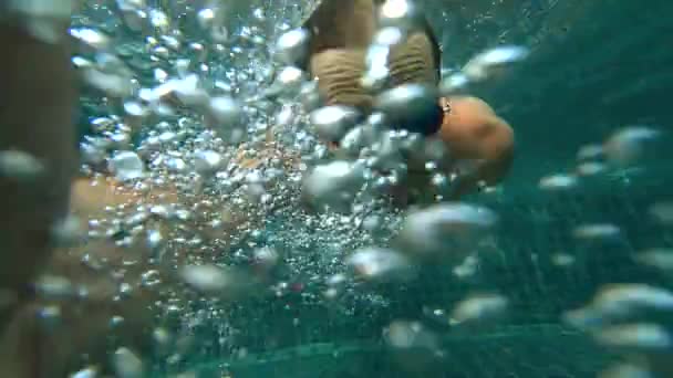 Un jeune homme blanc beau faisant un selfie sous-marin sur une caméra d'action. Portrait d'un jeune homme avec des lunettes se déplaçant devant la caméra sous l'eau. 4k — Video