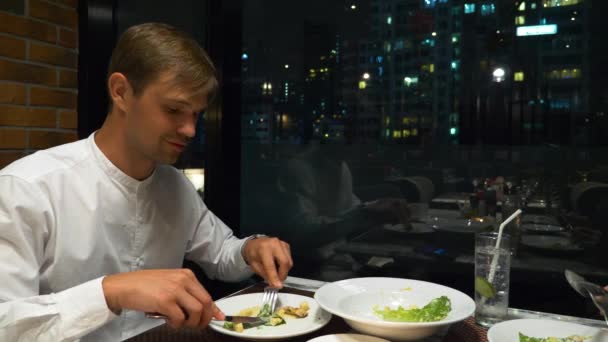 Casal feliz conversando e jantando em um bar com vista para arranha-céus, à noite, 4K, fundo embaçado — Vídeo de Stock