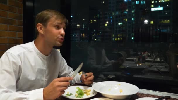 Pareja feliz hablando y cenando en un bar con vistas a los rascacielos, por la noche, 4k, fondo borroso — Vídeos de Stock