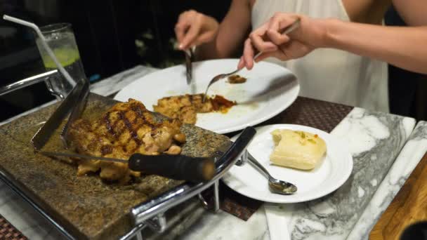 Alguien para hablar y cenar en el bar con vistas a los rascacielos, por la noche, 4k, difuminar el fondo. Las manos femeninas cortan un trozo de filete con un cuchillo y un tenedor . — Vídeo de stock