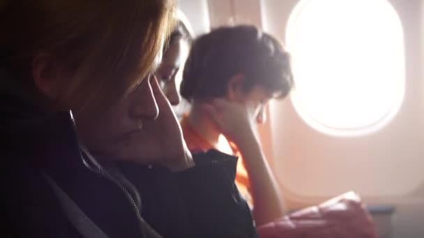 Женщина в самолете с детьми на фоне иллюминатора. 4k самолет вошел в зону турбулентности. девушка начала паниковать — стоковое видео