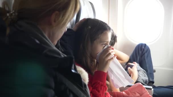 Femme dans un avion avec des enfants sur un fond hublot. 4k l'avion est entré dans la zone de turbulence. la fille a commencé à paniquer, elle respire dans un sac en papier . — Video